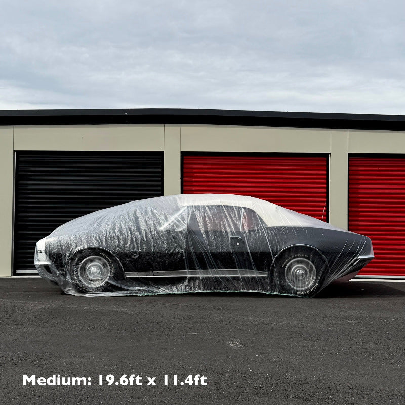 Car wrapped in plastic in front of a storage unit with dimensions displayed.